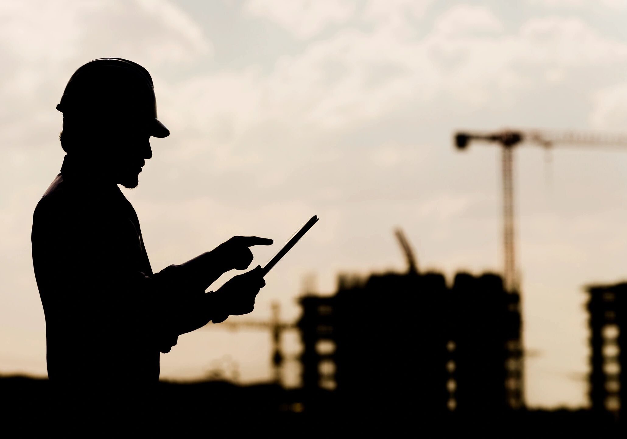 A man in a hard hat is holding a tablet.